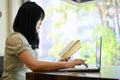 Asian female college student using laptop, doing her online homework in the coffee shop Royalty Free Stock Photo