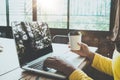 Side view of charming young hipster girl hands working on her laptop sitting at wooden table in a coffee shop. Royalty Free Stock Photo