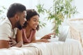 Side view of cheerful african couple using laptop in bed Royalty Free Stock Photo