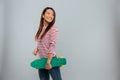 Side view of cheerful asian woman in sweater holding skateboard Royalty Free Stock Photo