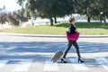 Side view of the cheerful business woman carrying the luggage while holding a red shoulder bag Royalty Free Stock Photo