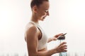 Smiling sportswoman with bottle of water at home