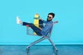 Side view of cheerful young man sitting in shopping cart Royalty Free Stock Photo