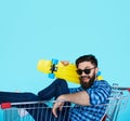 Side view of cheerful young man sitting in shopping cart Royalty Free Stock Photo