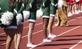 Side view of cheerleaders standing on the track infront of the stands during a football game Royalty Free Stock Photo