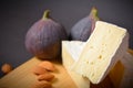 Side view of Cheese platter of Soft French Brie cheese cuts served with almond nuts and fig berries on wooden board