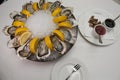Side view close up food shot of fresh raw shucked open oysters lying between lemon slices on a round cold ice tray next to
