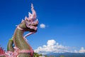 Side view of colorful traditional serpent statues on bannister of Thai temple against cloud on blue sky with beautiful rural scene Royalty Free Stock Photo