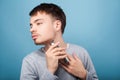 Side view of concentrated brunette man shaving neck, isolated on blue background