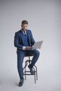 Side view of concentrated businessman in armchair working on laptop. dressed in three piece suit Royalty Free Stock Photo