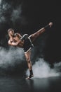 Side view of concentrated muay thai fighter practicing kick on black Royalty Free Stock Photo