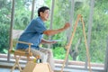 Side view of concentrated senior man painting picture on easel at home Royalty Free Stock Photo