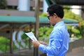 Side view of confident young Asian business man looking charts or paperwork and thinking his work in urban city background Royalty Free Stock Photo