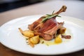 side view of confit de canard with crispy skin on potatoes