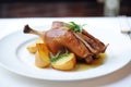 side view of confit de canard with crispy skin on potatoes