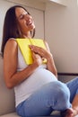 Content pregnant woman holding book