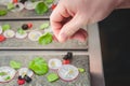 A cook adds a pinch of salt to an artistic plating of micro green and radish salad.