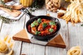 Large sausage in tomato sauce in cast iron pan