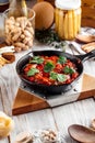 Large sausage in tomato sauce in cast iron pan
