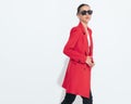 side view of cool fashion woman with sunglasses buttoning red coat Royalty Free Stock Photo