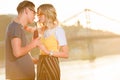 side view of couple drinking beverage with two plastic straws from one bottle on river beach Royalty Free Stock Photo