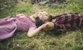 Side view couple lying on grass and looking at sky. Young people relaxing in park or forest. Summer holiday romance