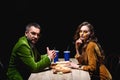side view of couple in stylish velvet clothing sitting at table with fried onion rings french fries and sauces Royalty Free Stock Photo