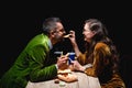 side view of couple in stylish velvet eating fried onion rings french fries and sauces at table Royalty Free Stock Photo