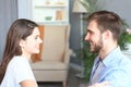 Side view of a couple talking sitting on a couch and looking each other at home. Royalty Free Stock Photo