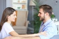 Side view of a couple talking sitting on a couch and looking each other at home Royalty Free Stock Photo