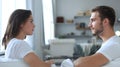 Side view of a couple talking sitting on a couch and looking each other at home. Royalty Free Stock Photo
