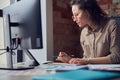 Side view of creative woman, interior architect or designer wearing glasses working on a project, using computer while Royalty Free Stock Photo