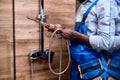 Side view on cropped repairman handyman in blue overalls holding shower handle in hands