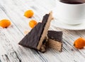 side view crunchy waffle cake with cup of black tea and kumquat on white wooden background