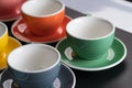 Side view cup of coffee colorful alternating colors is bright Red, Yellow, Orange, Green, Gray, Black and saucer for background in Royalty Free Stock Photo