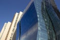 Side view of a curved blue glass window wall of a modern and elegant corporative building, next to a yellowish classical one. Royalty Free Stock Photo