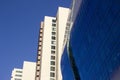 Side view of a curved blue glass window wall of a modern and elegant corporative high-rise building, next to a yellowish classical Royalty Free Stock Photo