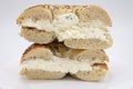 A Cut in Half Large Poppy Seed Bagel filled with Cream Cheese on a White Plate with a White Background Royalty Free Stock Photo