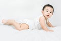 Side view of cute asian baby boy is lying on bed on white blanket. Still unable to walk. Crawling only and looks at camera on a Royalty Free Stock Photo