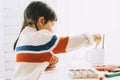 Side view of cute Caucasian child little girl painting and drawing with brush and watercolor on white desk at home. Royalty Free Stock Photo