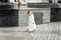 Side view of cute funny caucasian blond kid boy wearing white pool spa bathrobe scolded walking by tiled stone floor Royalty Free Stock Photo