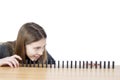 Side View Of Cute Girl Looking At Lined Up Dominoes On Wooden Table Isolated On White Background Royalty Free Stock Photo