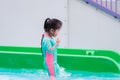 Side view of cute little girl playing in the water park. Adorable kid wearing a mint green thermal swimsuit. Happy children. Royalty Free Stock Photo