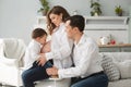 Side view of cute pregnant woman resting with family at home. Little boy kissing belly of mother while happy father Royalty Free Stock Photo