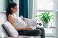 pregnant woman on grey sofa with computer on knees working as freelancer at home Royalty Free Stock Photo