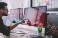 Side view of data analyst pointing with finger at charts on computer monitor while testing protection