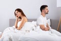 Despaired married couple sitting on bed