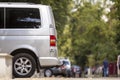 Side view detail of white passenger medium size luxury minibus van parked on summer city street pavement with blurred silhouettes Royalty Free Stock Photo