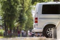 Side view detail of white passenger medium size luxury minibus van parked on summer city street pavement with blurred silhouettes Royalty Free Stock Photo