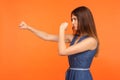 Side view of determined brunette girl with fighting spirit in casual dress punching with fists Royalty Free Stock Photo